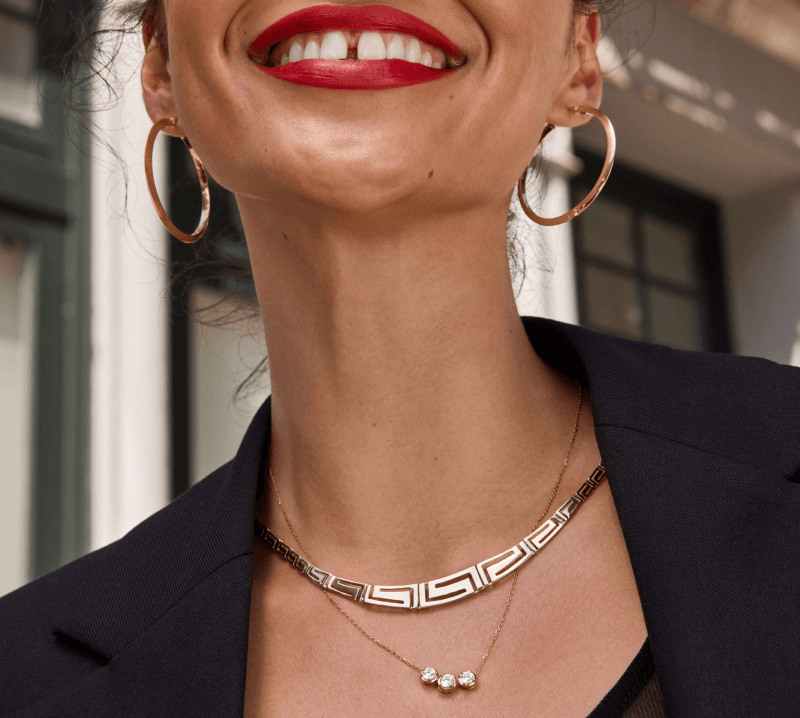 A woman is pictured smiling, adorned with 10K & 14K Gold Earrings & Necklaces.