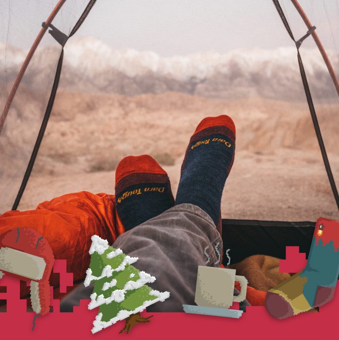 Shop Darn Tough Socks - a camper wearing Darn Tough socks inside a tent, surrounded by holiday-themed bitmap images.