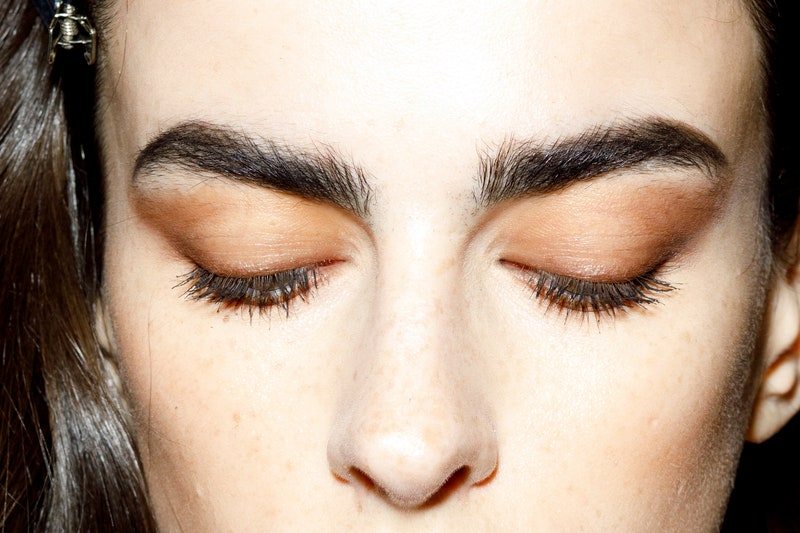 a model with bold full threaded eyebrows and red lipstick poses backstage at Elisabetta Franchi during Milan Fashion Week Fall/Winter 2022/2023
