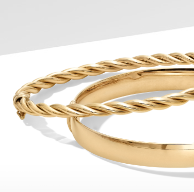 Two gold bracelets stacked on top of each other, one smooth and the other in a twisted rope pattern