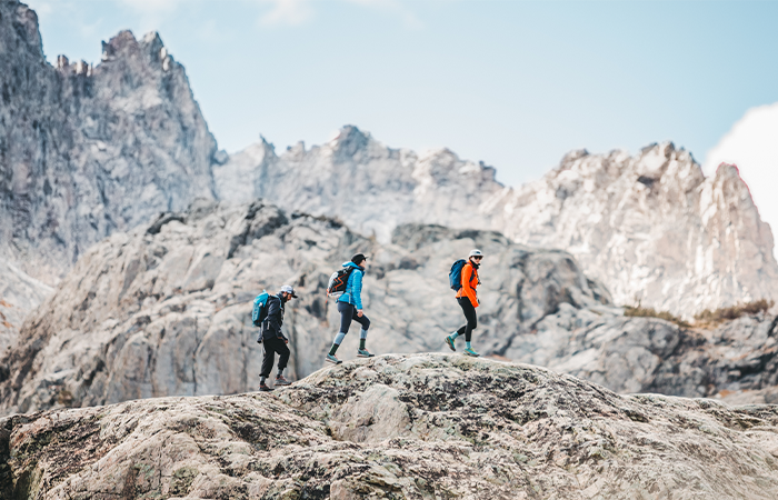 A group of three traverses a rocky landscape.