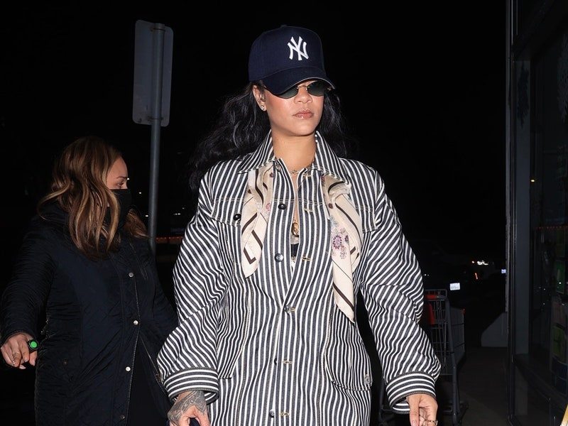 Image may contain: Rihanna, Baseball Cap, Cap, Clothing, Hat, Sleeve, Long Sleeve, Coat, Jacket, Adult, Person, and Shirt