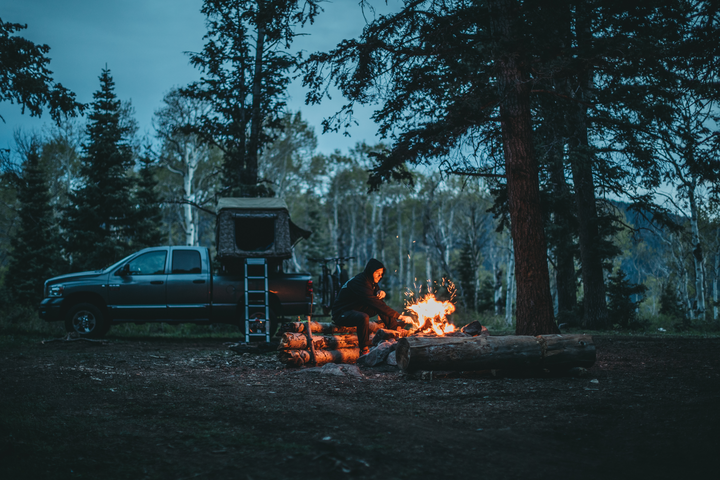 Jeremy stokes the fire at a campsite at dusk