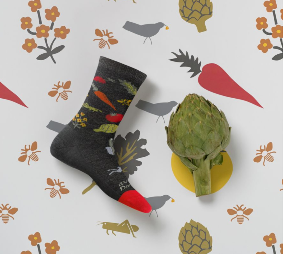 Our super awesome printed Foodbank Farmer's Market sock laying atop a background of its own print #SoMeta ... oh, and there's an artichoke beside it (and printed on it)