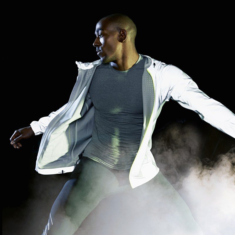 a man in a black studio with fog wearing athletic gear