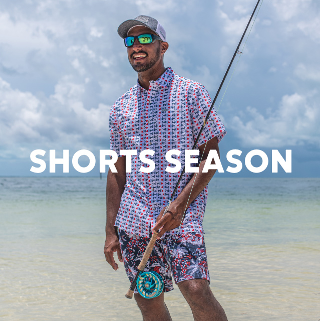 A fisherman in a patterned top and shorts at the shoreline with the headline SHORTS SEASON. 