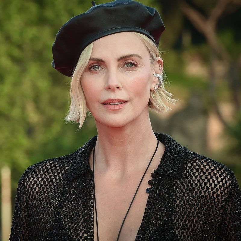 Charlize Theron photographed outdoors wearing a black beret and black top.