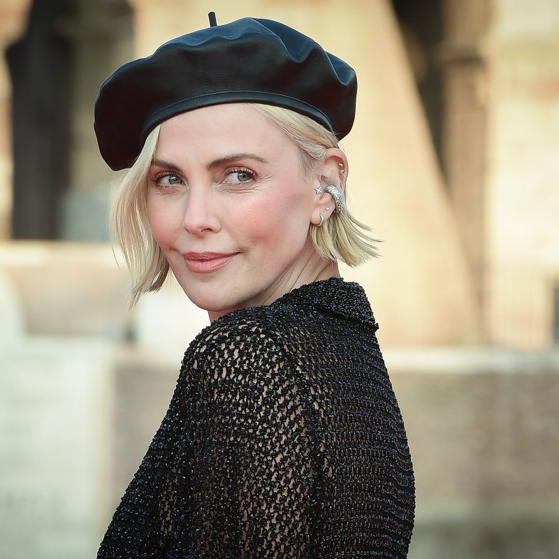 Charlize Theron photographed outdoors wearing a black beret and black top.