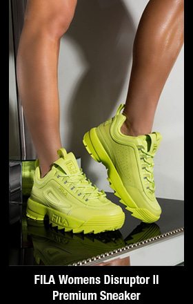 FILA Womens Disruptor II Premium Sneaker In Lime features a neon base and "dad shoe" silhouette. Crafted from faux leather, this 80&squot;s inspired sneaker features a chunky sole, stamped logo detailing, and a lace-up fit.
