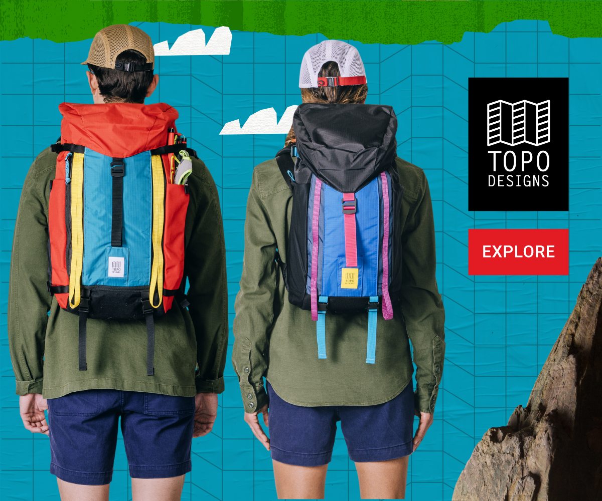 TWO PEOPLE FACING BACKWARD, SHOWING THE SIZE DIFFERENCE BETWEEN MOUNTAIN PACK 28L AND 16L WITH THE TOPO DESIGNS LOGO IN THE CORNER