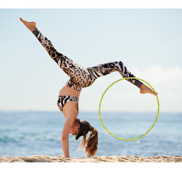 Model doing gymnastic with hula hoop, wearing CAMILLA leopard print leggings and crop