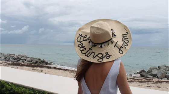woman in a straw hat that says "greetings from"