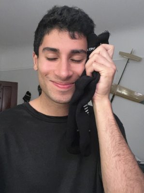 A reviewer holds a pair of black Darn Tough socks to his face and smiles