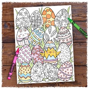 Partially colored-in coloring page of easter eggs with flowery designs, next to pink and green crayons