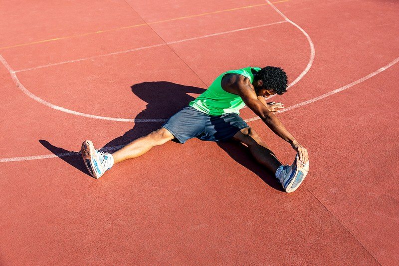 Man stretching on a red athletic court