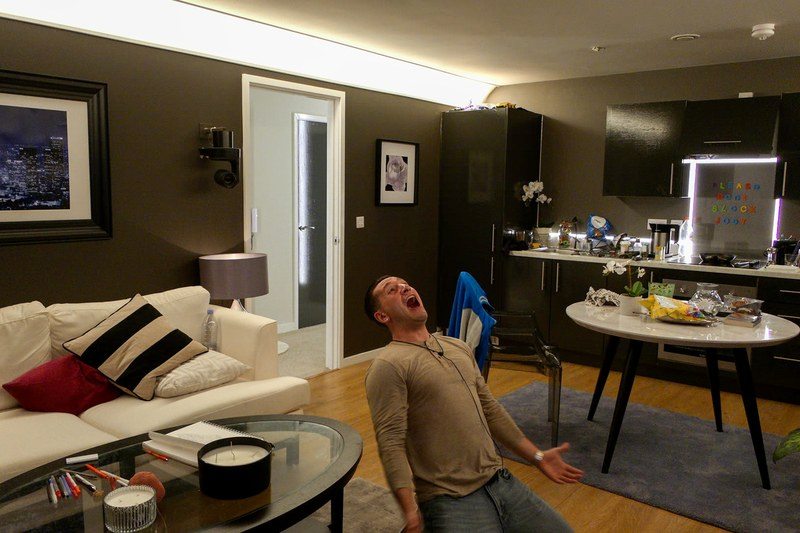 a man kneeling on his living room floor shouting
