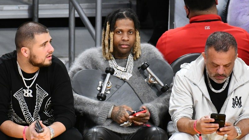 Lil Durk, wearing a gray sweater that is interwoven with a spliced skateboard, attends a basketball game between the Los Angeles Lakers and the Milwaukee Bucks at Crypto.com Arena on February 09, 2023 in Los Angeles, California.