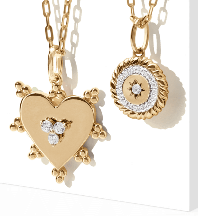 Image of two gold chain necklaces with pendants - one is a heart with diamonds, the other a circular design with diamonds throughout