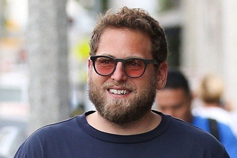 Jonah Hill smiling and walking down the street