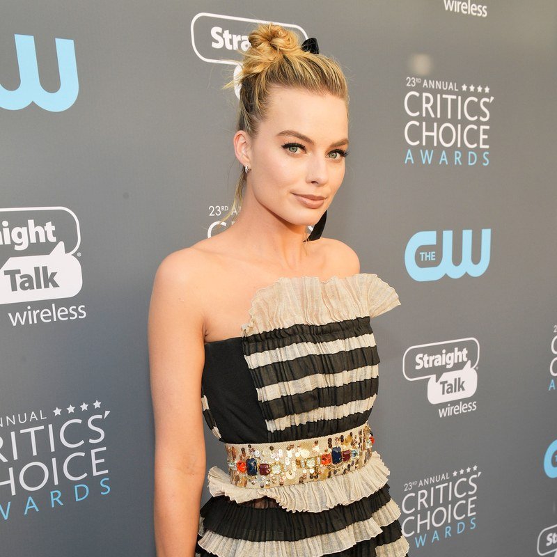 Margot Robbies pairs a cat eye with a beribboned updo.