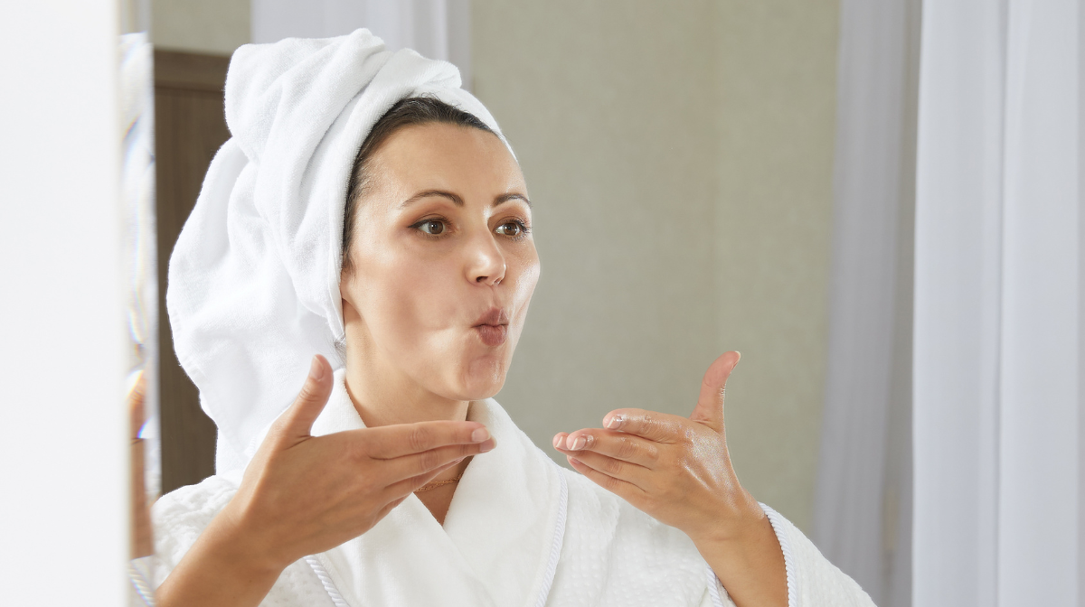 Woman practicing her face yoga exercises in the mirror.