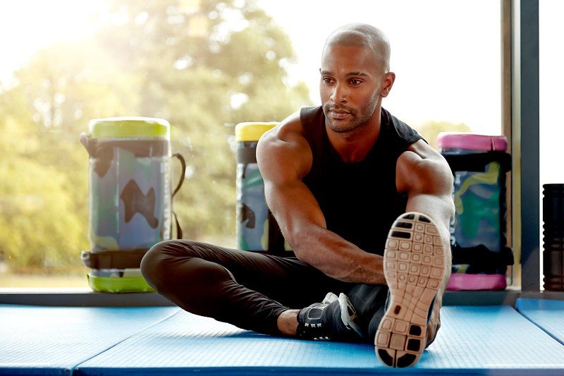 Young man stretching on a mat in workout clothes