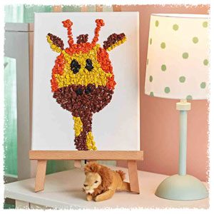 A miniature canvas of a giraffe made from crayons, sitting on a nightstand next to a stuffed lion toy and lamp