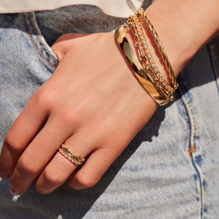 Gold jewels shine bright on this woman's hand while she reaches in her jean pocket.