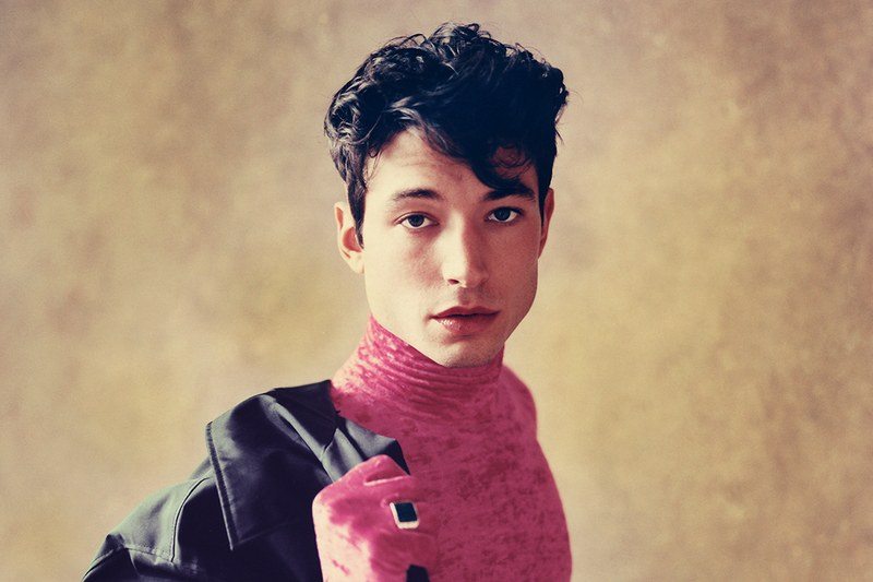 ezra miller putting on a jacket looking great