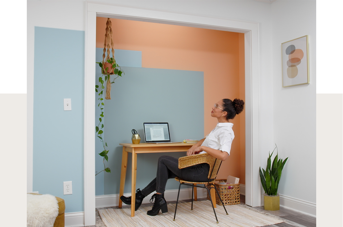 Image of a person sitting in their office space with multiple colored rectangles painted on the wall.