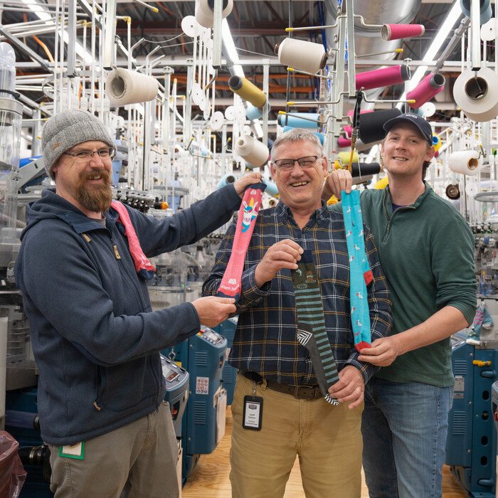 Darn Tough dads and their kids who work with them, all holding up their recommended socks for Father's Day gifts