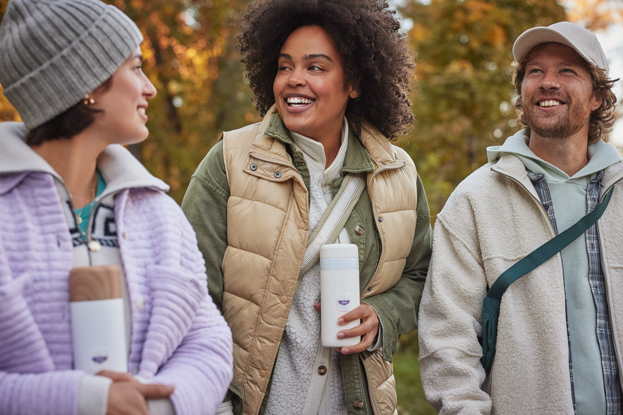 A man and two women take a walk holding thermoses full of Yogi Tea