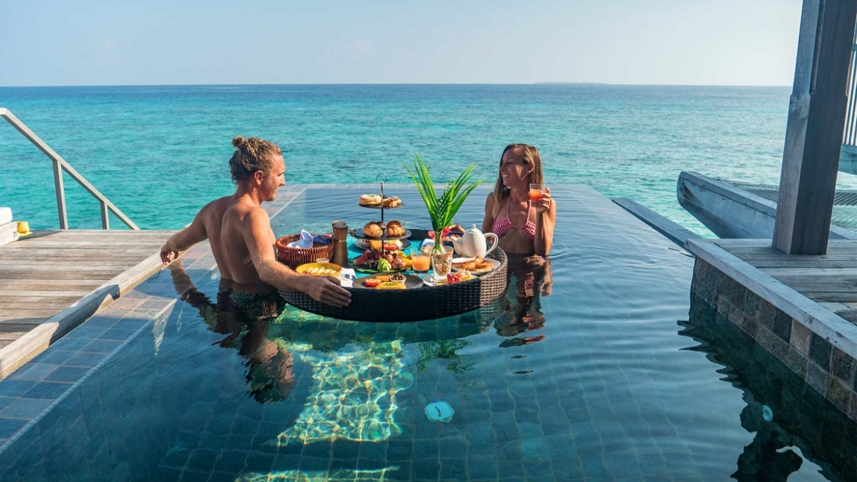 Couple having breakfast in pool overlooking the water