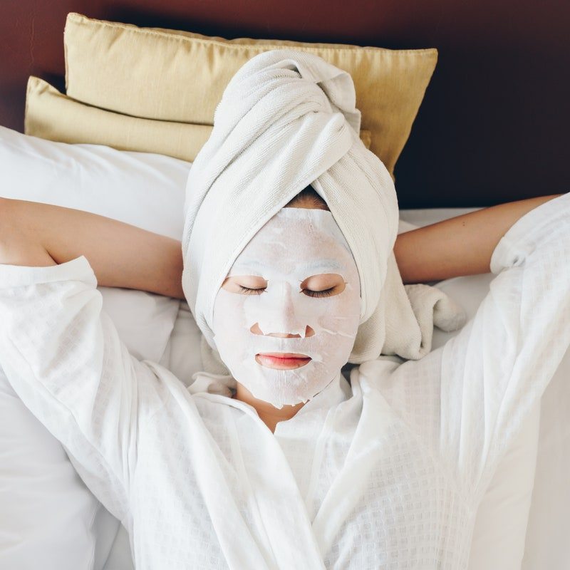 Portrait of young woman sleeping on bed with face mask to enhance her skin.